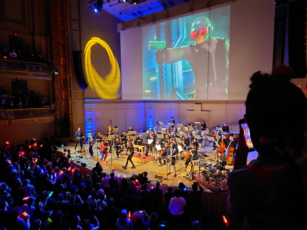 Performance of "I Am... All of Me". On the screen above is the scene from I think Shadow the Hedgehog of one of the G.U.N. soldiers about to shoot Maria.